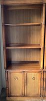 Tall wood bookcase cabinet with open upper shelves and lower cabinet with cane doors.