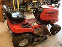 Side profile view showing mower deck, seat, steering wheel, and side discharge chute