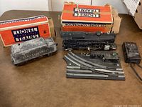 Photo of Lionel train set items including locomotive, tender, track, and controller with original boxes in background.