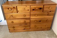 Front view of the pine dresser showcasing 10 drawers with square wood pulls and natural wood grain pattern.