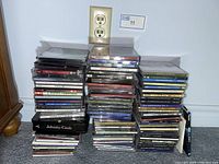 Photo showing stacks of various CDs arranged on the floor with visible titles like Johnny Cash and multiple others.
