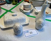 Salt and pepper shakers, covered butter dish with lid, and oil dispenser displayed on a table with other tableware