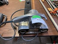 Side view of Corded Sears Craftsman 3 inch belt sander with power cord lying on wooden table.