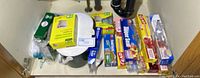 Variety of kitchen wraps, bags, and compost pail arranged under kitchen sink