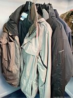 Three Columbia jackets hanging on hangers showing style, color and brand details