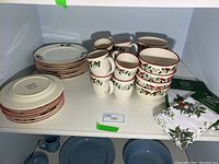 Full set of Pfaltzgraff Cardinal Holly dishes including plates, bowls, mugs, tea towels, and oven gloves arranged on shelf