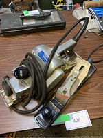 TECOmaster electric planer with black cord wrapped around it alongside Stanley Handyman hand plane on wooden table.
