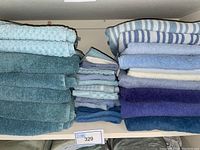 Stack of blue towels in darker and lighter shades showing bath towels and smaller towels including striped and textured patterns.