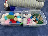 Two large clear plastic storage bins containing assorted yarn and knitting supplies, taken to show full lot contents and storage method.