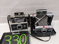 Front angled view showing both Polaroid cameras with bellows and the instructional booklet partially visible.