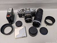 All items laid out: camera body, two lenses with hoods, flash unit, filter and caps