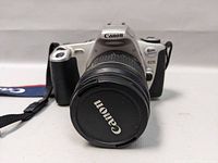 Front view of Canon Rebel 2000 SLR camera with lens cap on the lens.