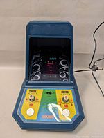 Front view of Coleco Galaxian 2380 arcade game showing control panel with dual joysticks, fire buttons, game selection, and score display on built-in screen.