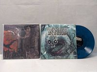 View of two vinyl records with their respective cover arts and Gates of Slumber blue vinyl partially out of its sleeve.