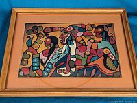 Front view of the framed indigenous style print artwork showing the abstract colorful figures and animals.