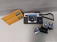 Kodak Instamatic X-15 camera with two flash units and manual on white background