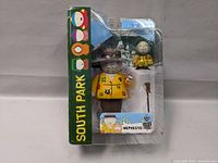Front view of sealed South Park Mephesto figure in original packaging showing the figure, mini figure, and accessory inside clear plastic clamshell with green South Park branded cardboard backing.