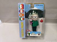 Front view of Mr. Garrison South Park figure in original packaging with accessories visible.
