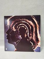 Front album cover with layered silhouette profiles of The Rolling Stones band members in artistic design.