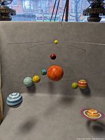 Photo of the solar system hanging mobile showing all planets suspended around the central sun with a neutral gray background