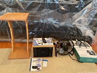 Wide shot showing all items in the lot including the wooden side table, air purifier, fan, and leg massager box on the floor.