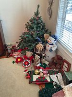 Full view of artificial Christmas tree with lights and assorted holiday decorations including bears, a snowman figure, candles, decorative napkins, and centerpiece tray.