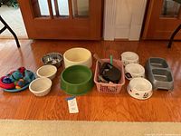 Front view of all items including bowls and dog toys spread on hardwood floor.