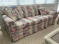 Front view of a three cushion sofa upholstered in floral fabric, showing patterns and cushions.