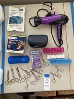 Photo of Remington hair dryer, cold packs, assorted personal care scissors, men's shaver case, and pill boxes on table
