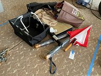 Photo showing three umbrellas with wooden handles, two tote bags including a 'Shop Bulk & Save' bag, and a black collapsible fabric carrier.