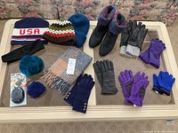 Photo of winter accessories including hats, scarves, gloves, and boots on table