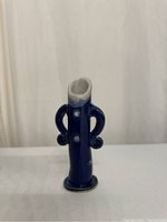 Front view of the blue pottery bud vase with curved handles and wide top opening.