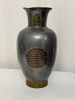 Full view of the tall vase showing brass and aluminum materials with a decorative Asian emblem on the body and brass accents on rim and base.