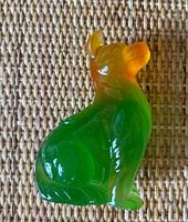 Side view of dog glass figurine showing orange to green color gradient and carved details