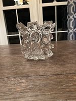 Side view of clear molded glass decor piece on wooden surface with front window background