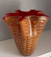 Photo showing the vase's exterior orange and white wave pattern and six-flared ruffled top with red interior.