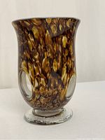 Front angle view of the handblown vase showing the brown and amber mottled color and one oval cutout