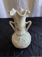 Front view of light tan Belleek dual handled vase with hand painted clovers.