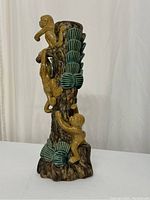 Side view of the ceramic candle holder featuring three yellow monkeys climbing a brown tree trunk with green leaves.