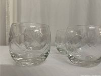 Four clear lowball glasses with diamond cut patterns photographed on a white surface with a neutral background.