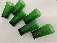 Six green bubble pattern drinking glasses with a dark base, shown lying on their side.