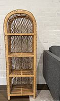 Front view of the vintage arched wicker shelving unit showing four shelves and lattice work backing.