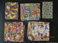 Five pieces of children's cotton fabric folded and displayed on black background showing their colorful patterns.