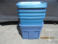 Full stack of 6 blue Rubbermaid storage tubs with lids in outdoor lighting, showing overall condition and size range.