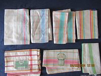 Photo of 7 folded vintage striped linen dish tea towels showing various stripe patterns and colors.