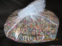 Plastic bag filled with assorted colorful glass seed beads from the front view.