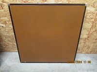 Vintage card table folded flat showing bottom side with brown panel and dark trim edges.