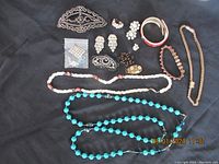 Full view of assorted costume jewelry pieces displayed against a black background including necklaces, bracelets, brooches, and earrings.