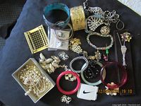 Top-down photo of the entire assortment showing multiple pieces of vintage costume jewelry including pearl necklaces, bangles, brooches, earrings, and a large gold-tone cuff bracelet.