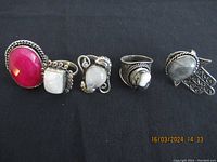 Five vintage sterling silver rings displayed side by side on black background, showing different stones and silver designs